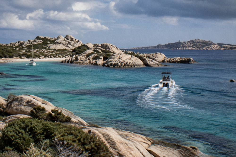 A motor boat heading out of a harbour toward open strait water