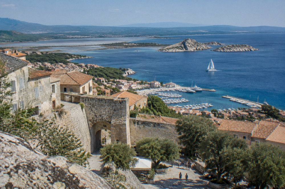 A sailing catamaran on open water near granite islands