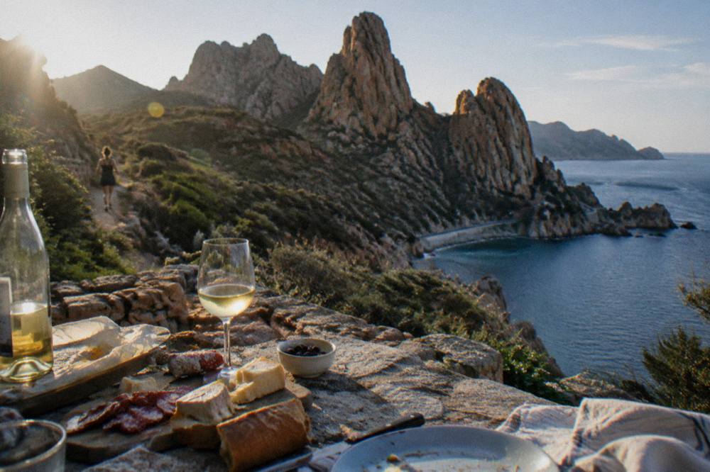 A table set with Corsican charcuterie, cheese and a glass of white wine