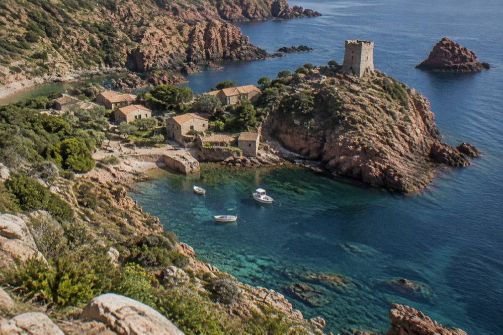 Red granite rock formations rising from the sea along a protected Corsican coastline