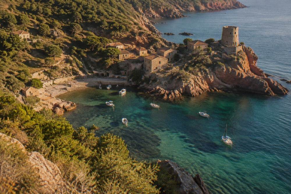 A small stone hamlet on a shoreline surrounded by wooded hills and clear water