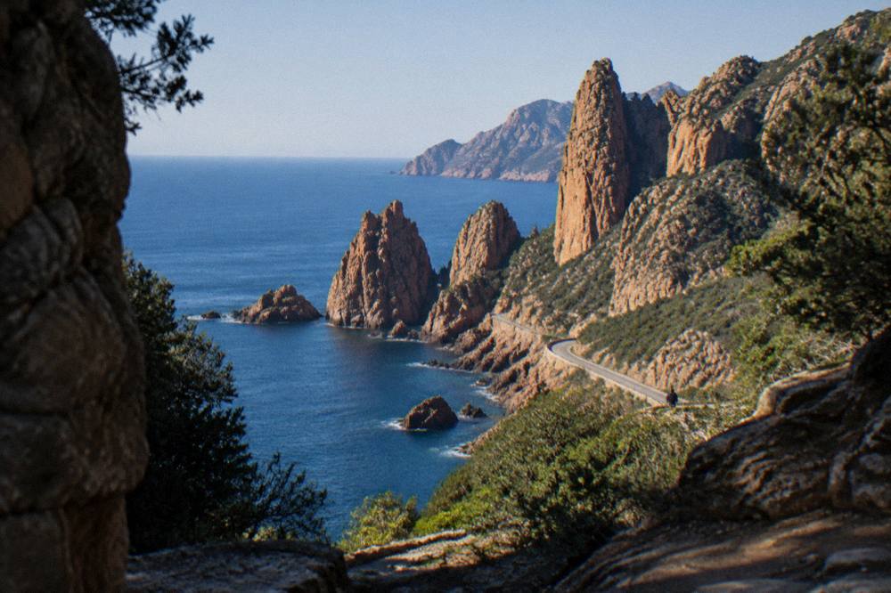 Red granite rock formations rising from the sea along the Calanques de Piana coastline