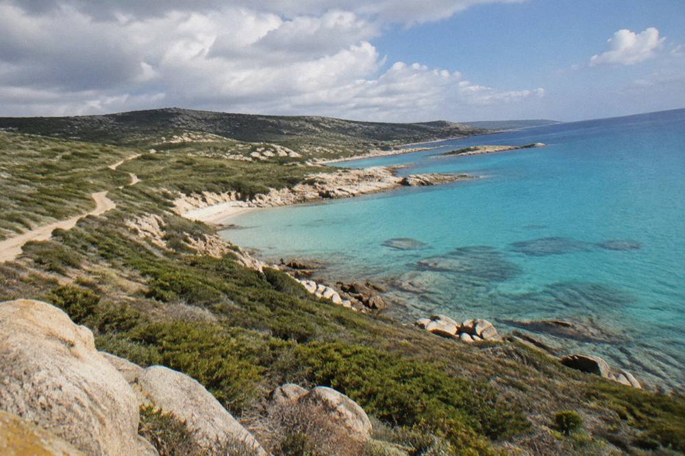 Turquoise shallow water over pale sand seen from a low cliff