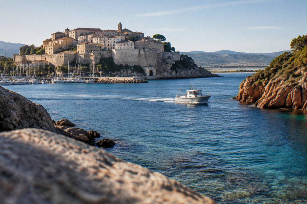 A boat passing red granite cliffs above clear water on a reserve coastline