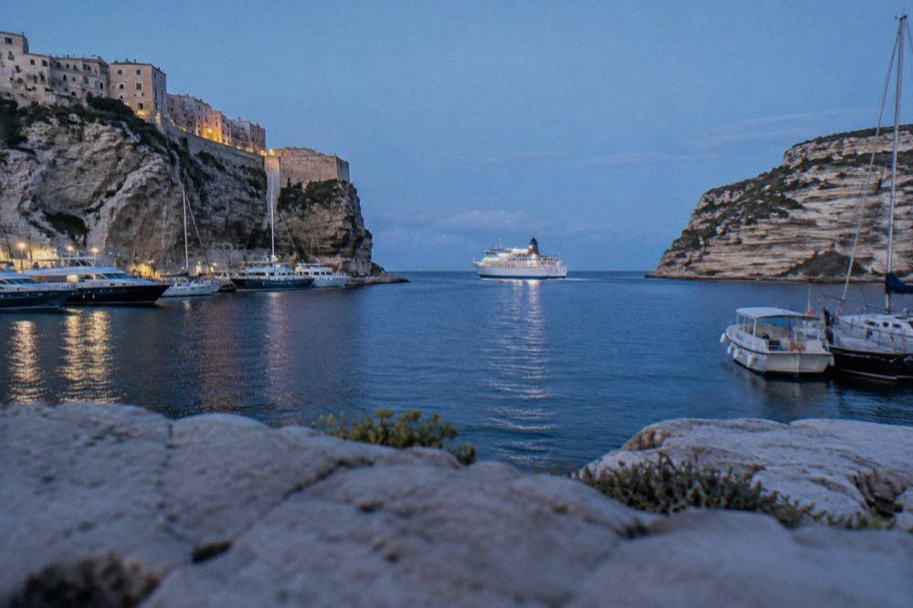 A ferry boat crossing open blue water between two coastlines