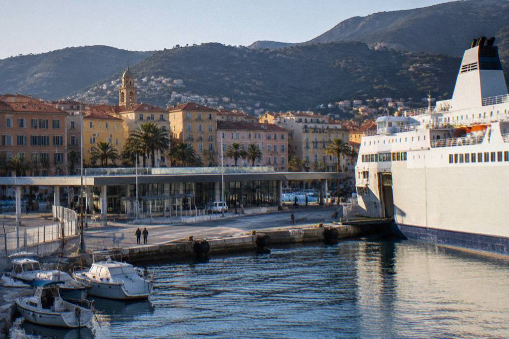A small ferry port with boats moored along a quay in evening light