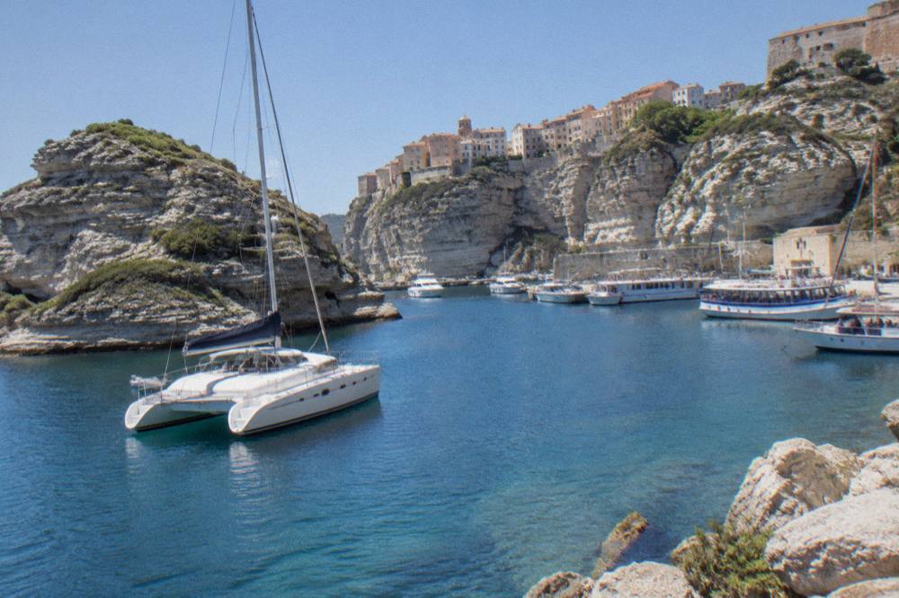 A catamaran anchored near granite islands in clear water