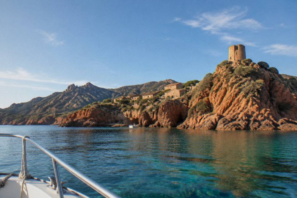 A boat deck view of red cliffs glowing in late afternoon light