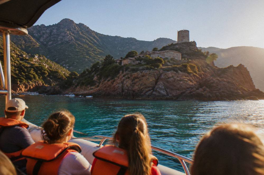 Passengers in life jackets seated on a small boat near cliffs