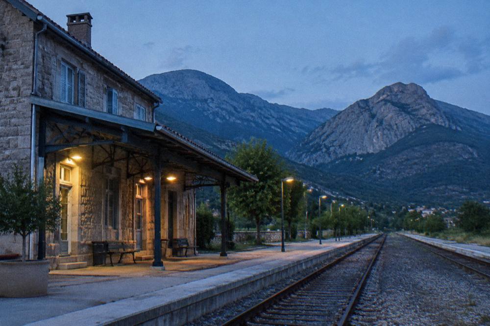 The platform of a small Corsican station with mountains in the background