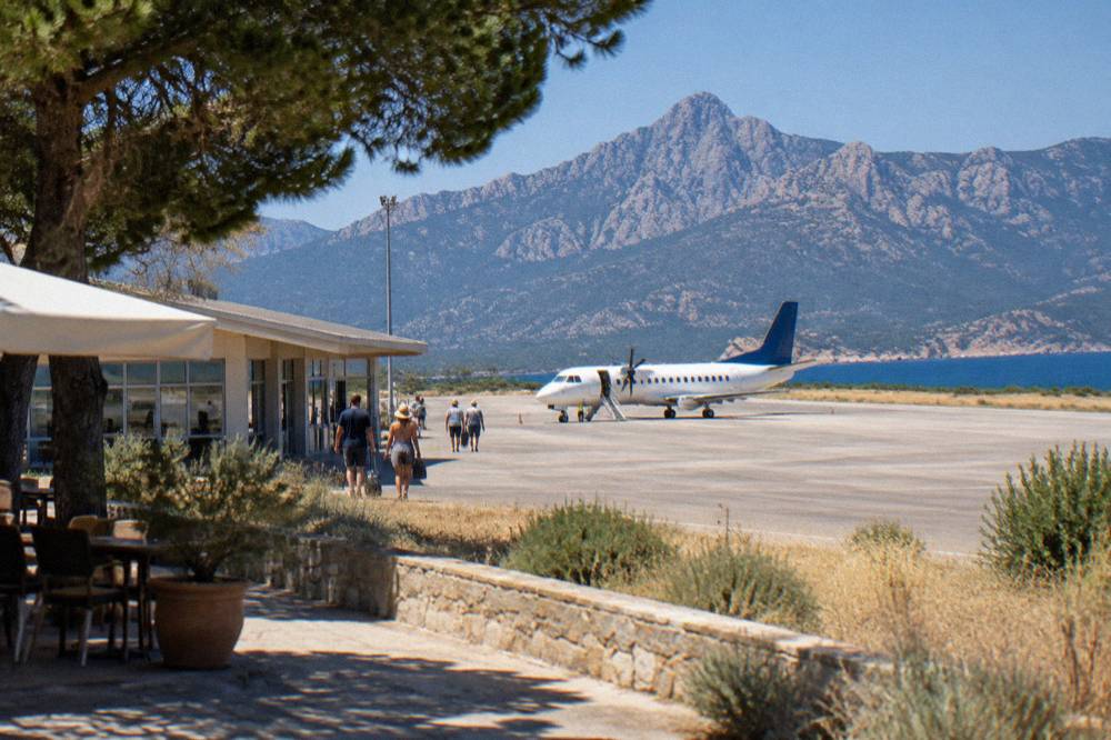 A departure board and terrace at a small regional airport in bright summer light