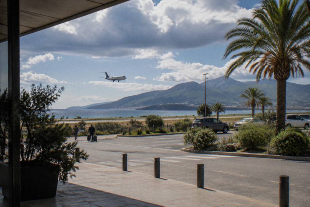 A regional airliner on approach over Mediterranean scrubland toward a runway beside the sea