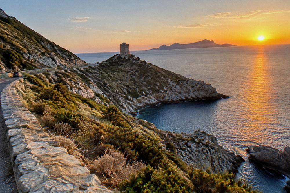Sunset over the Corsican coast with a rocky island silhouette on the horizon