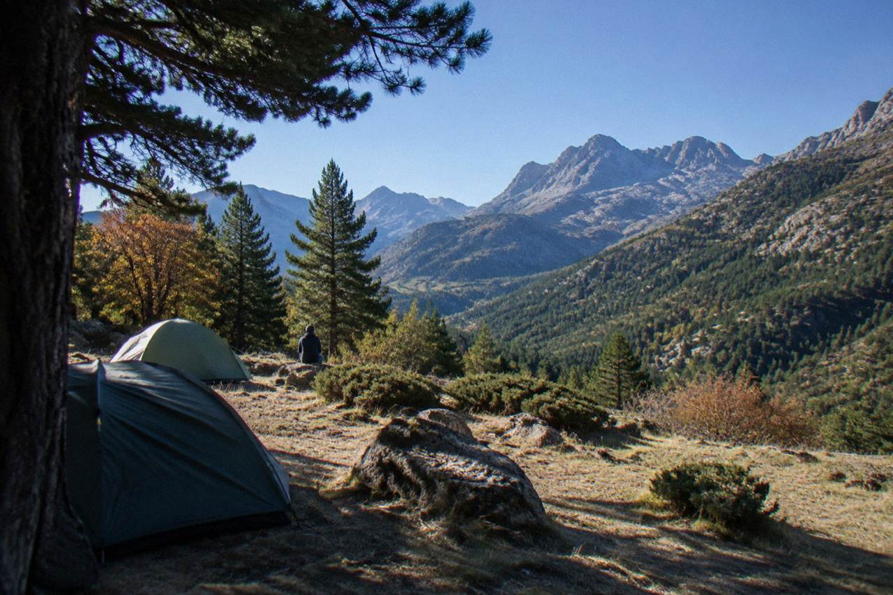 Tents pitched on a mountain terrace above a forested Corsican valley