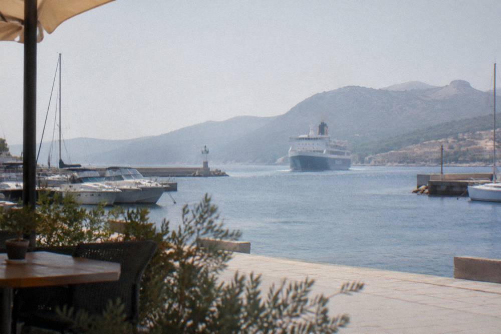 A ferry approaching a Corsican harbour town with hills behind it