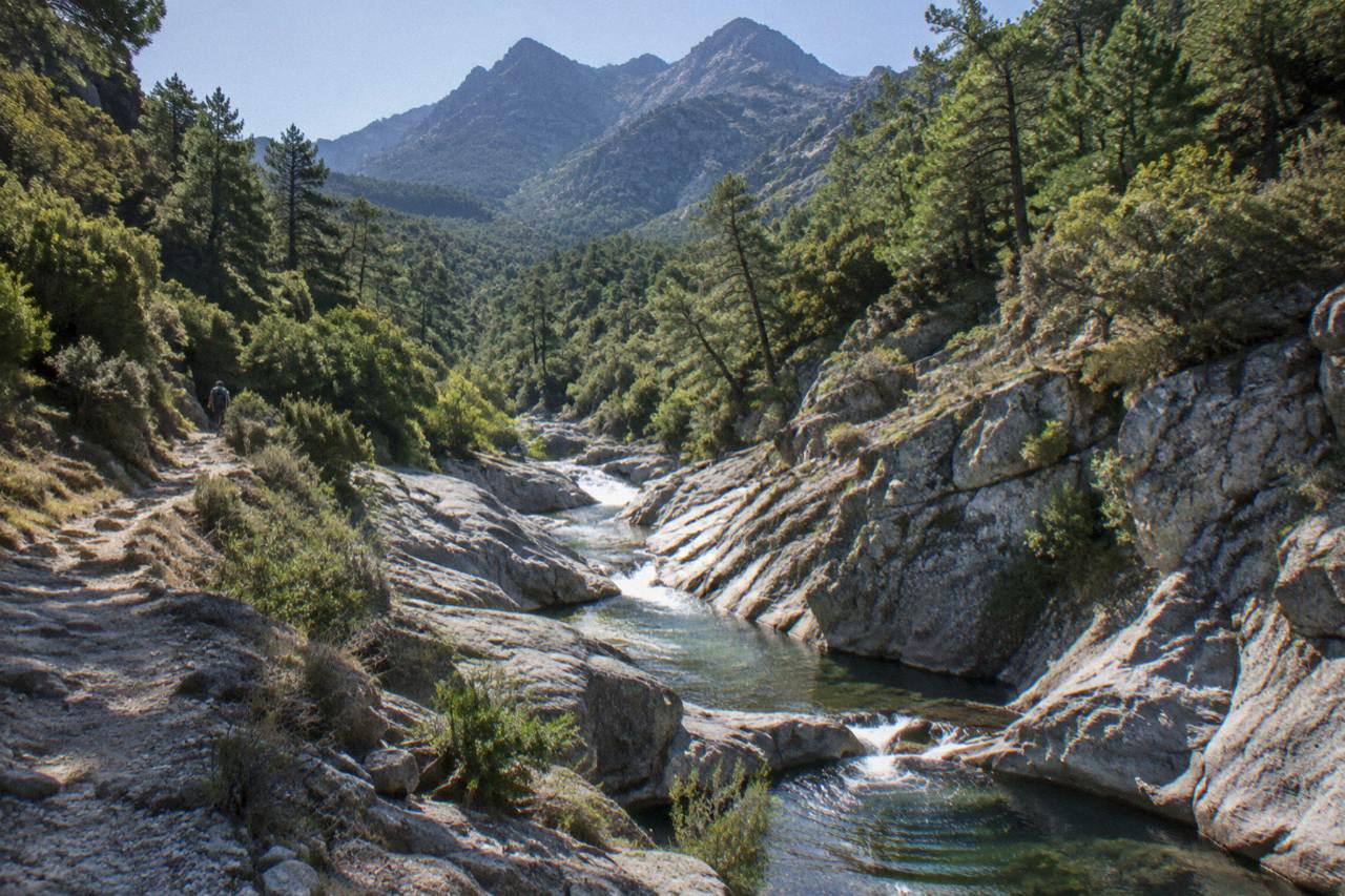 A narrow granite canyon in the Corsican mountains with clear water running between smooth rock walls