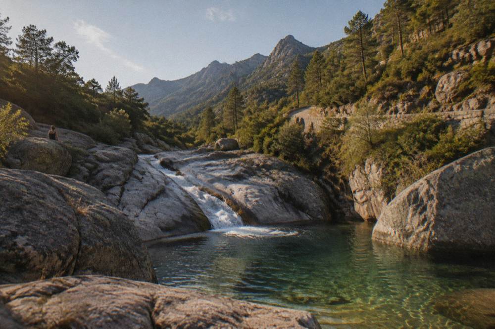 A clear mountain pool at the bottom of a rock slide in a shaded Corsican canyon