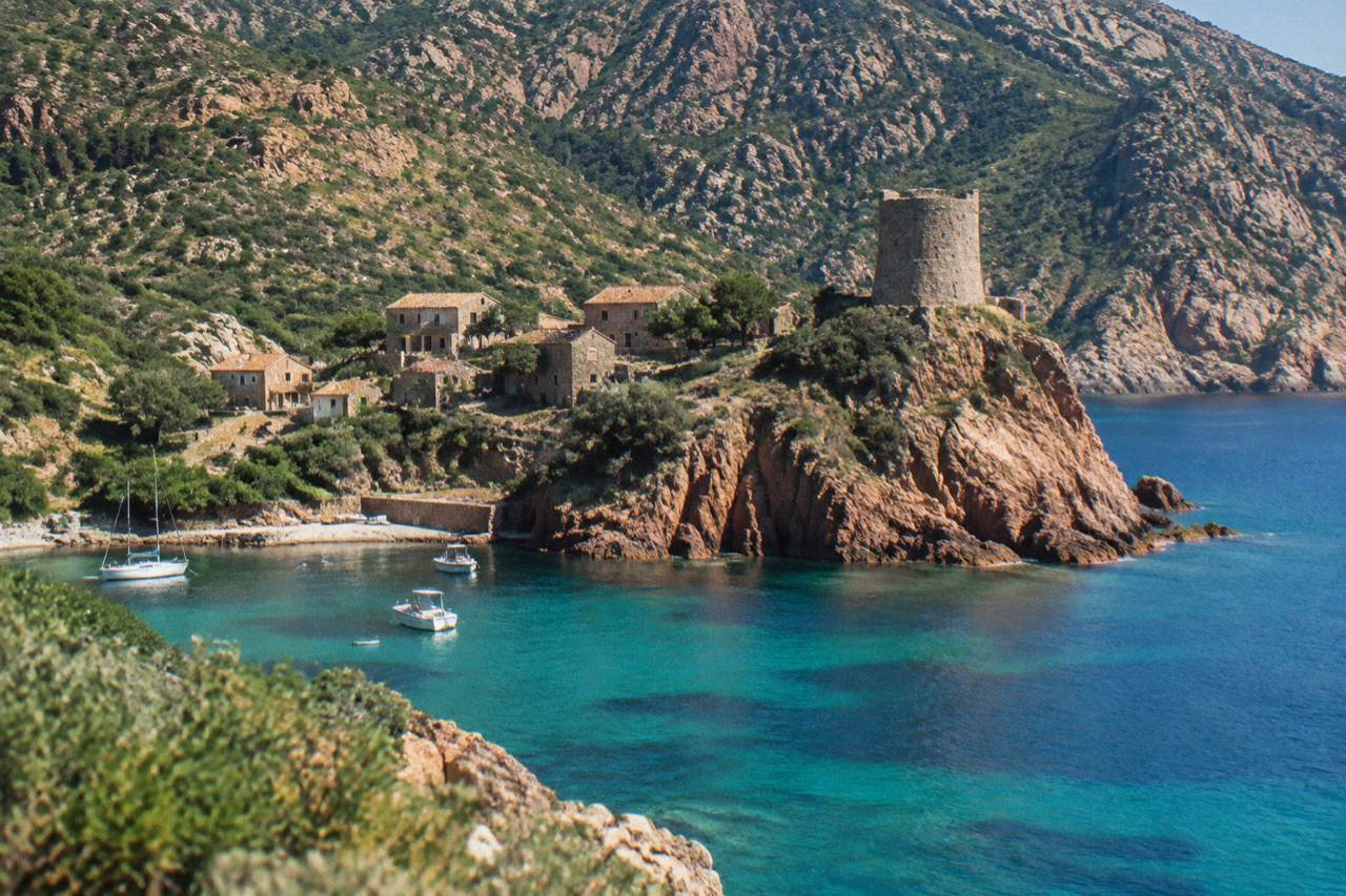 Stone watchtowers and a rocky Corsican hillside above the sea