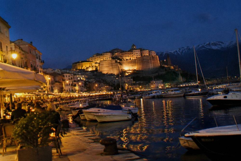 A harbour town at dusk with cafés along the waterfront
