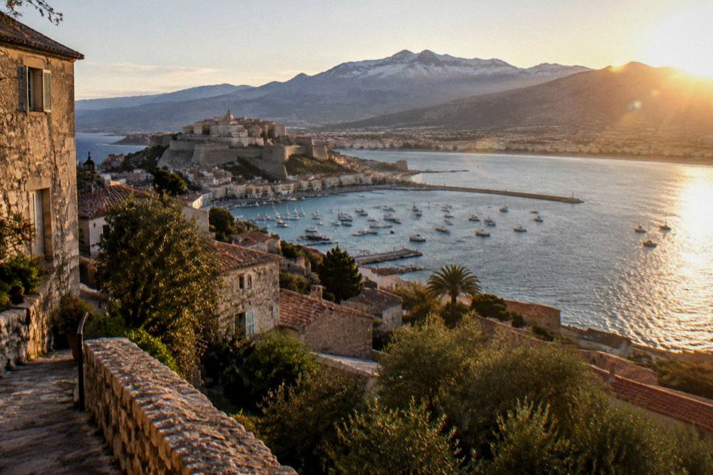 A stone village on a hillside above the sea at golden hour in Corsica