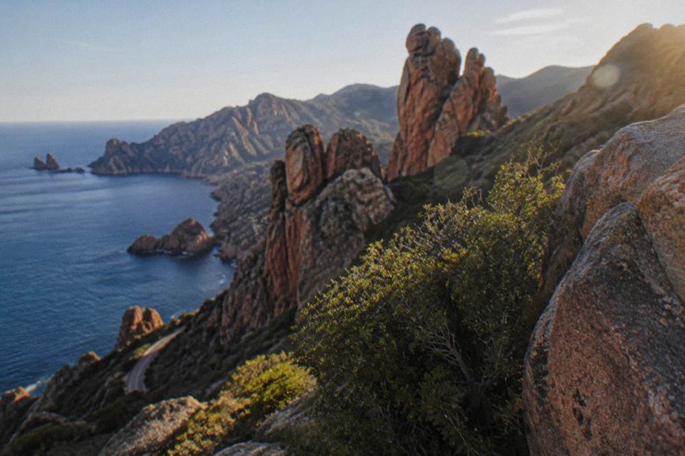 Red granite rock formations of the Calanques de Piana rising above the sea