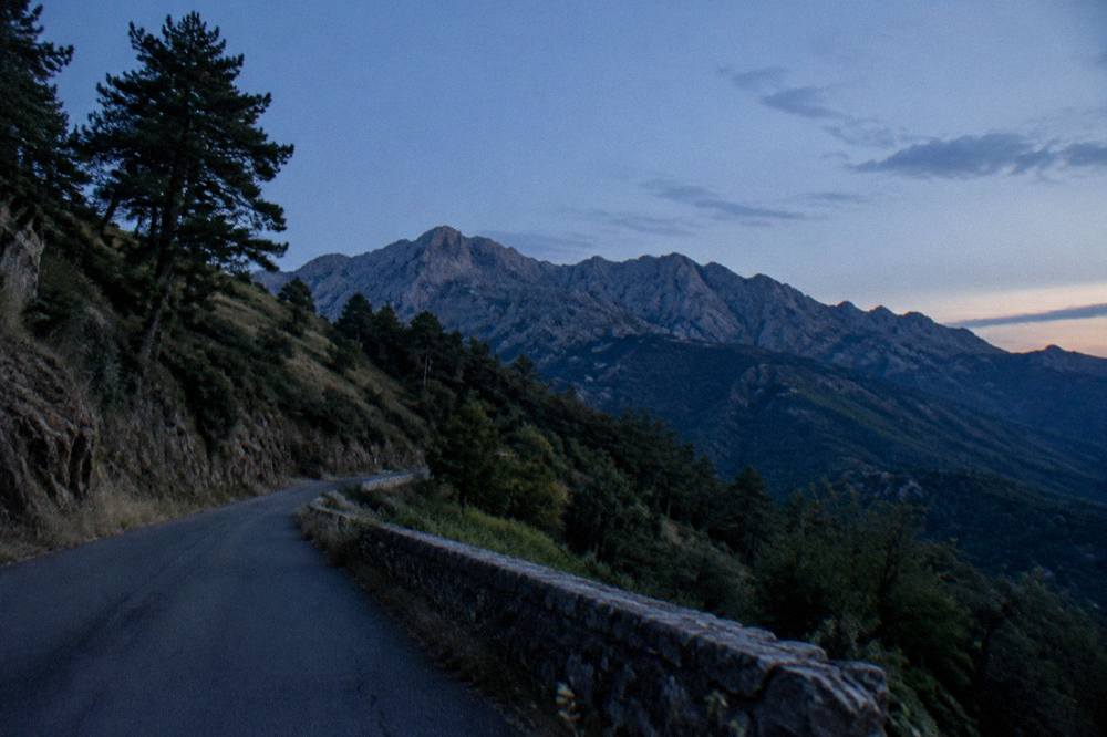 Narrow mountain road winding through Corsican hills with maquis vegetation