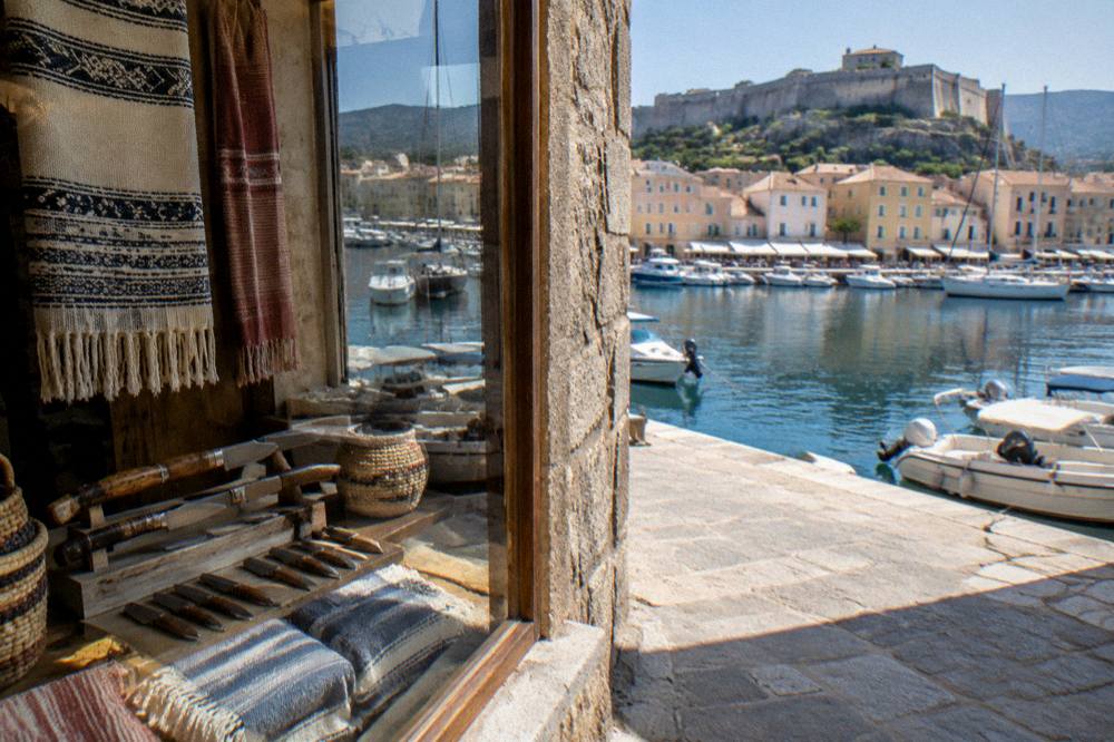 A craft shop window in a Corsican village displaying handmade knives and woven cloth