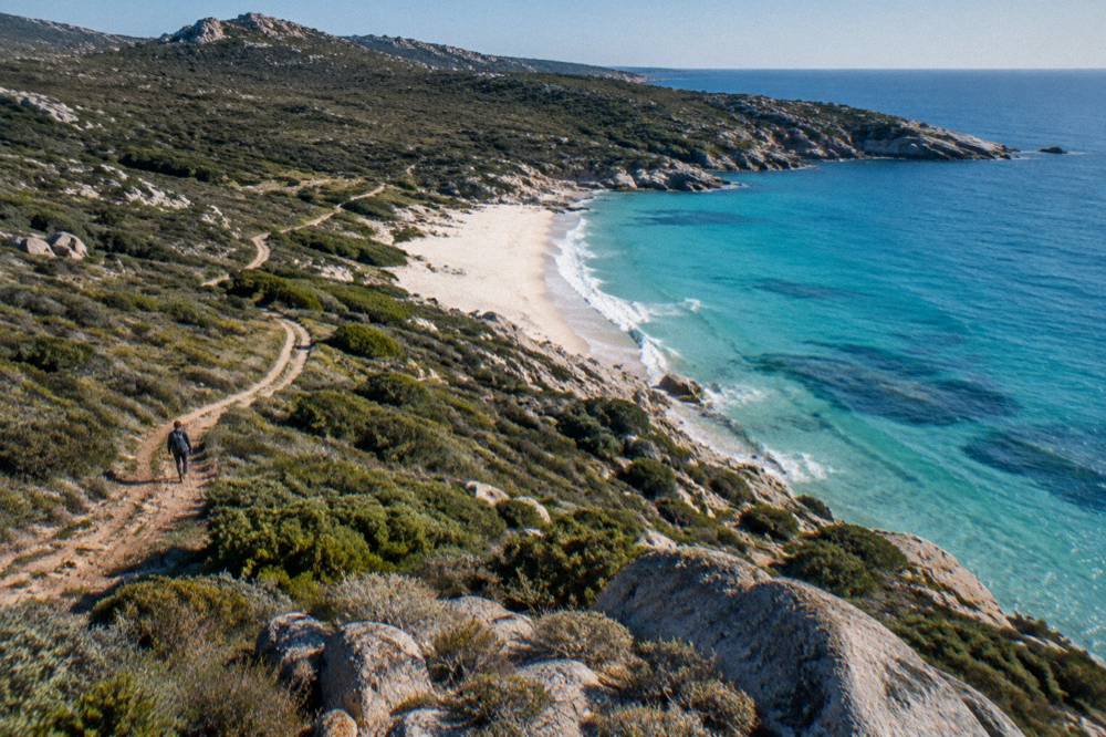 Turquoise water washing onto the white sand of a beach in the Désert des Agriates