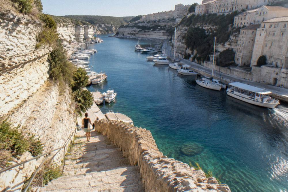 A stone stairway descending a cliff face toward clear water below