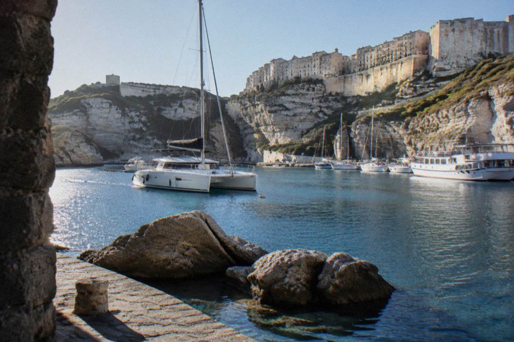 A catamaran anchored near granite rocks in a sheltered strait lagoon
