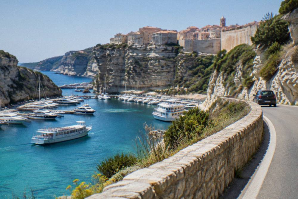 A coastal road winding above a rocky shoreline with turquoise water below