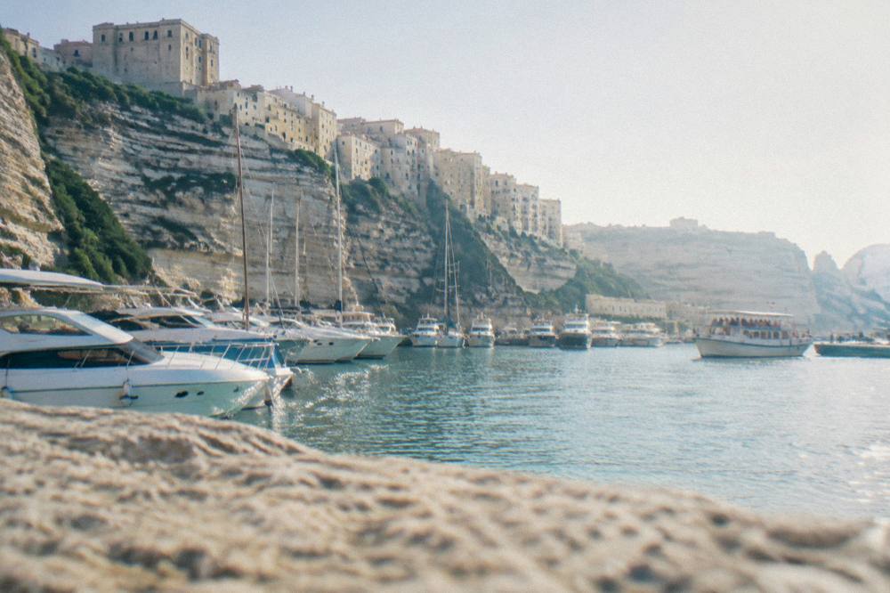White buildings of a harbour town stacked above a marina in evening light