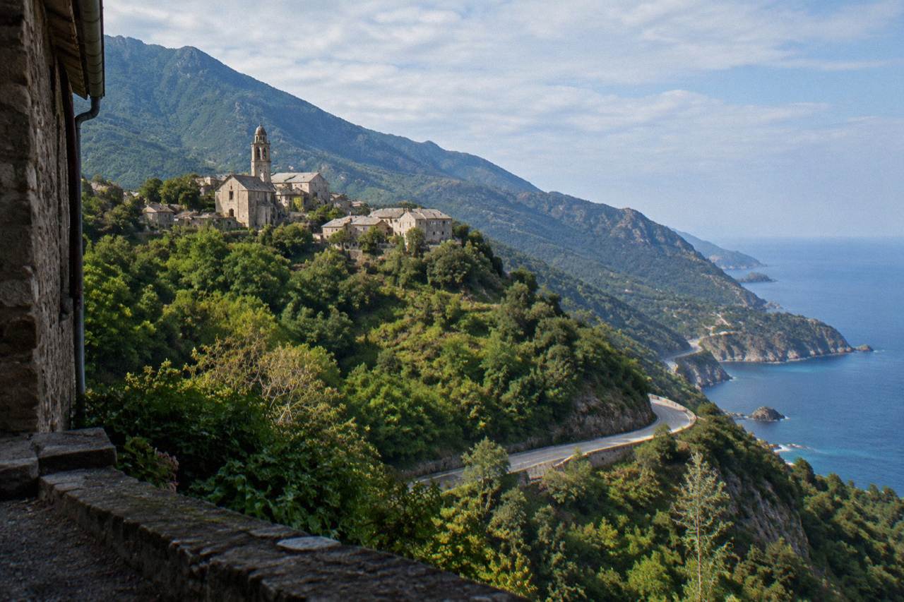 A mountain road winding along the Corsican coastline with blue sea and rocky cliffs