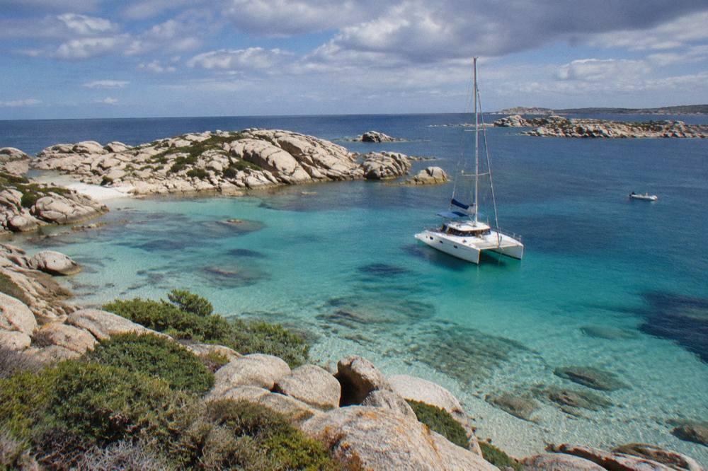 A catamaran anchored in turquoise water near the Lavezzi islands