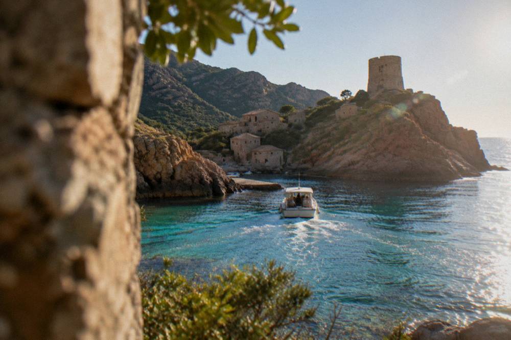 A boat entering the red rock inlet of Girolata on Corsica's west coast