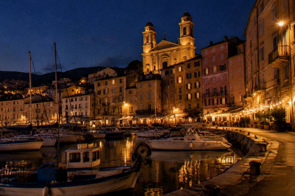 A harbour town at dusk with boats moored along the quay in Corsica