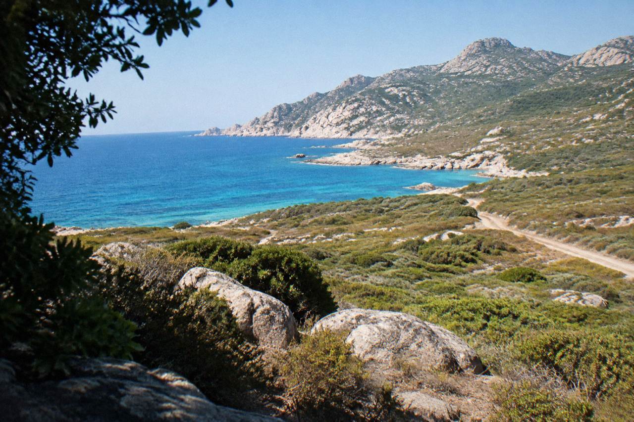 Granite cliffs of the Corsican coastline rising above clear Mediterranean water