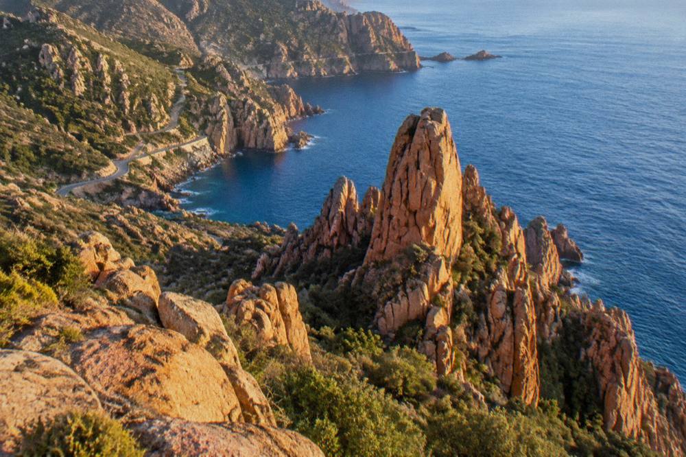 Red granite rock formations of the Calanques de Piana above the sea at golden hour