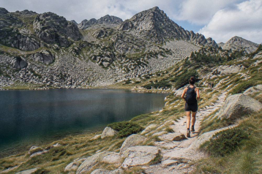 A marked mountain path climbing through granite terrain toward a Corsican ridge