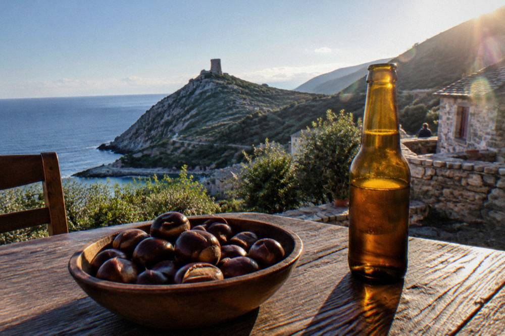 Chestnuts and a bottle of beer on a wooden table in a mountain village