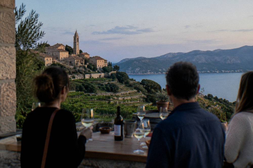 A small group standing at a winery tasting bar with glasses of white wine