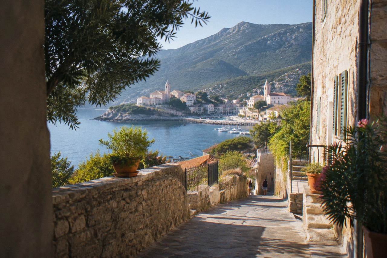 A stone village street in Corsica with mountains rising behind it