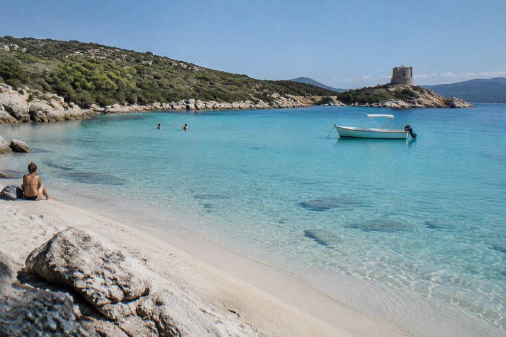 A small boat moored in a turquoise cove in southern Corsica