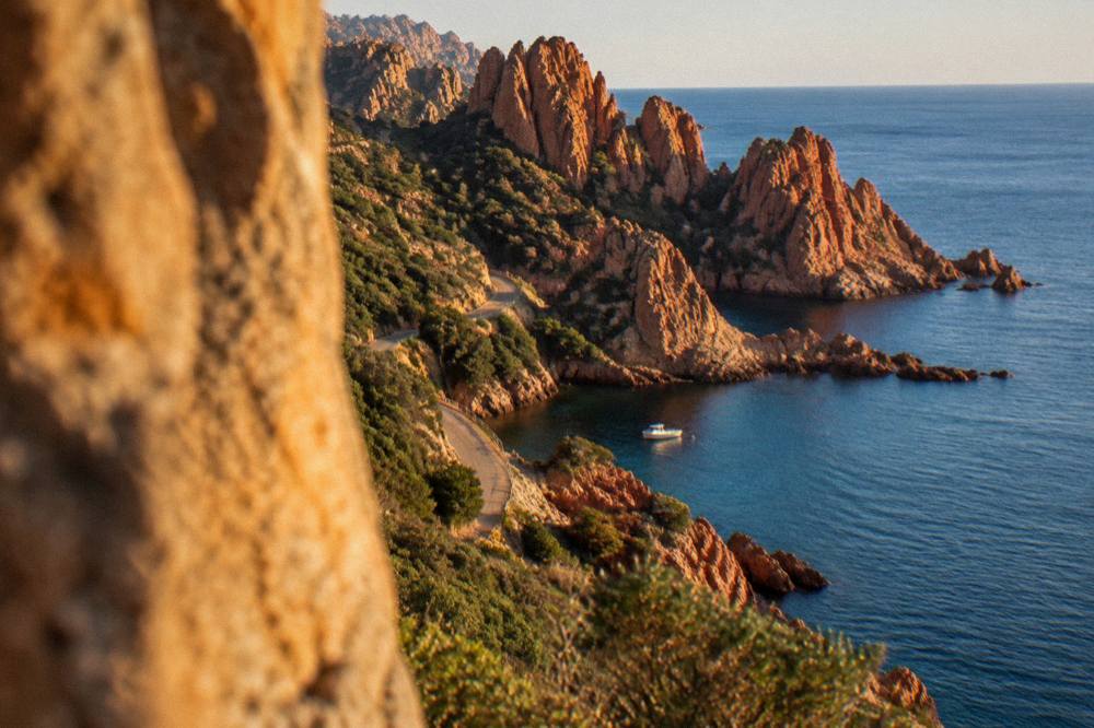 A small boat moored in a rocky cove near red cliffs on the Corsican west coast