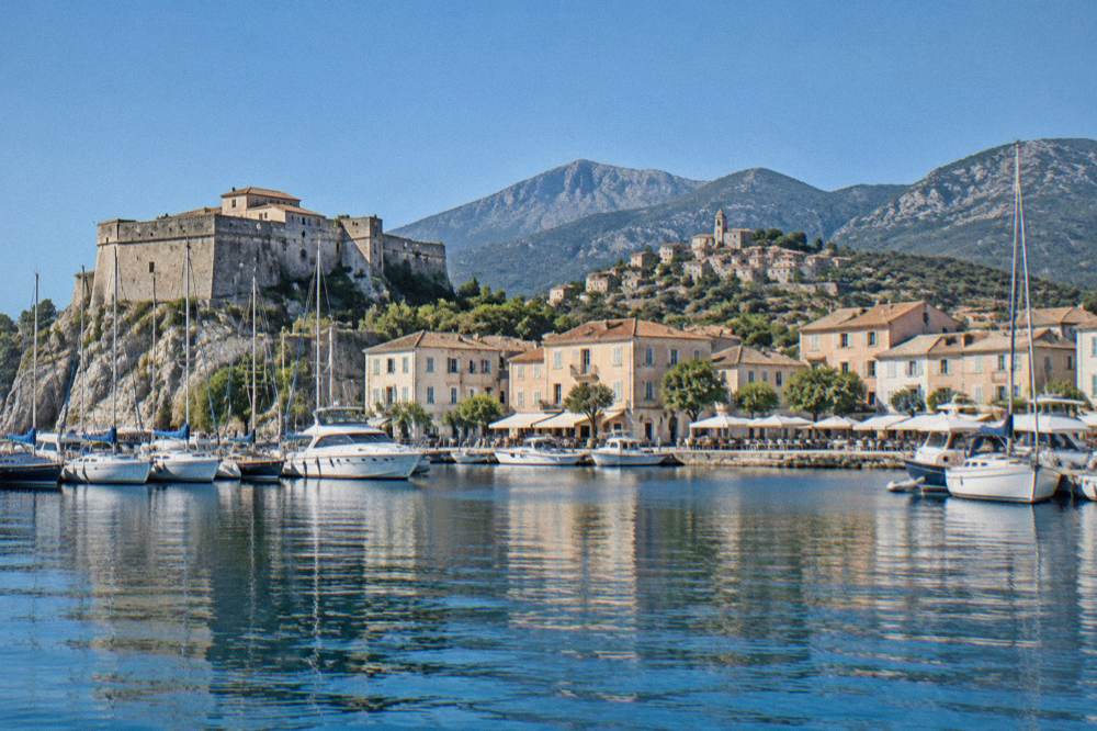 A stone hilltop village with terracotta roofs above Corsican mountains