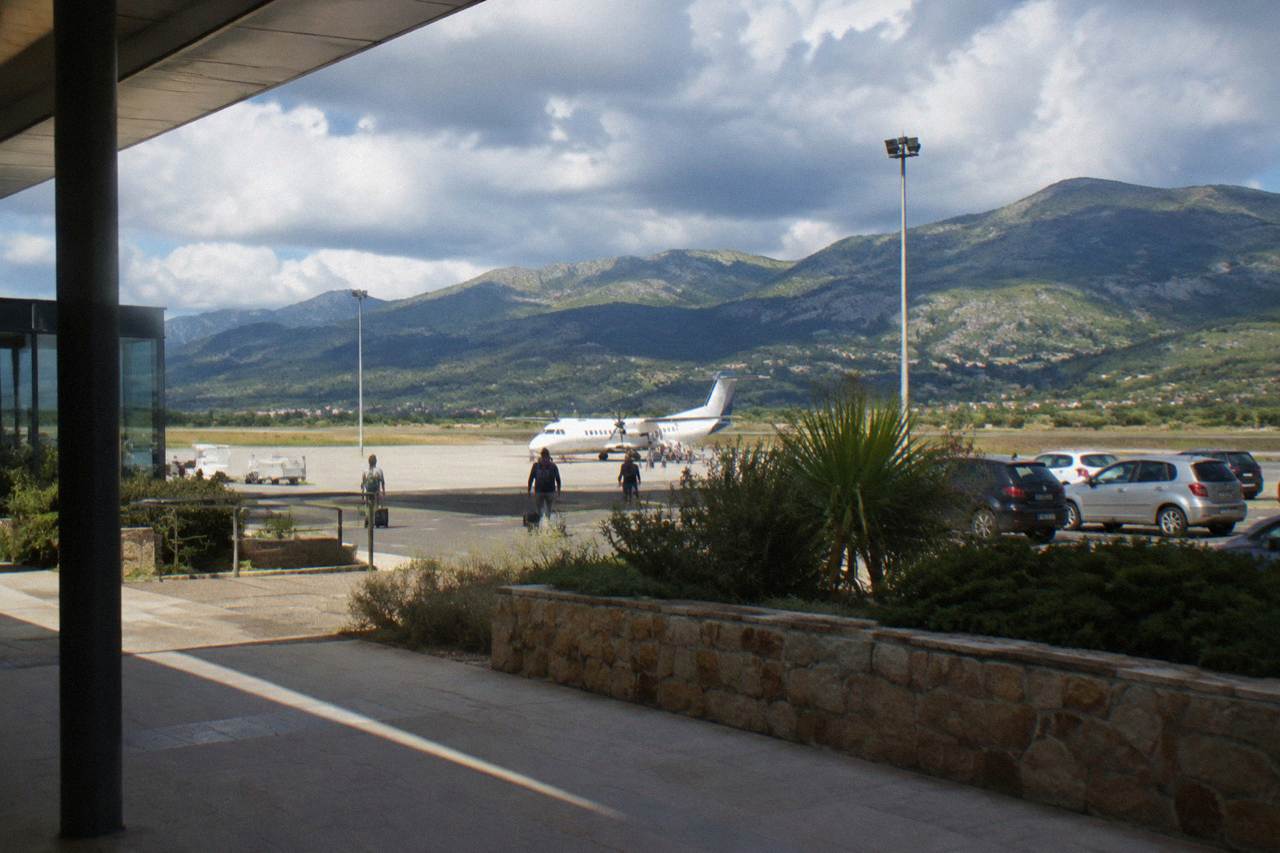 A small regional airport terminal at the foot of wooded hills in south Corsica