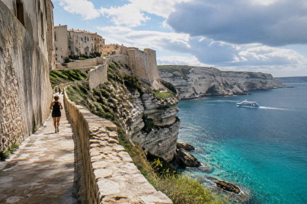 White limestone cliffs rising above a narrow strait with a small ferry crossing