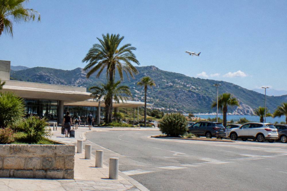 A small passenger aircraft banking over dark green mountains above the sea
