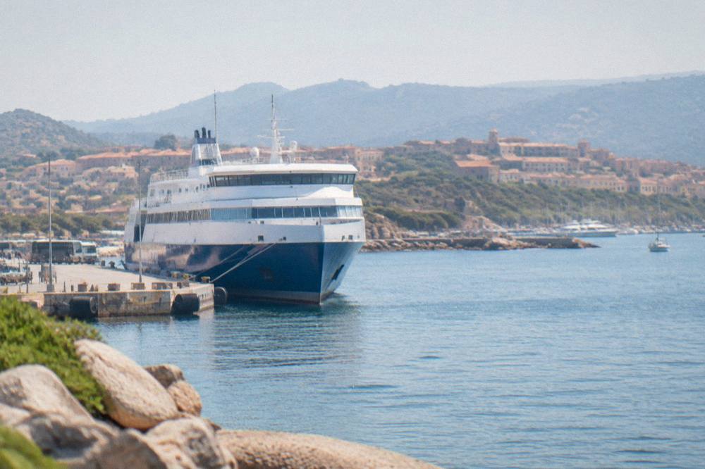 A passenger ferry docked at a Corsican port with the town rising behind it