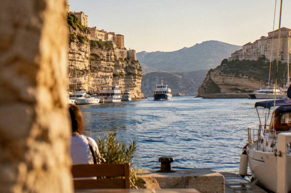 A ferry approaching a harbour town with mountains behind it
